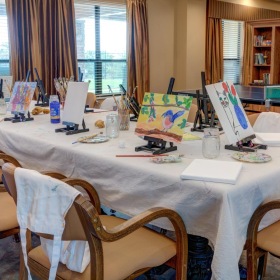 Enjoy our resident-only features table in art room with canvas paintings drying on stands